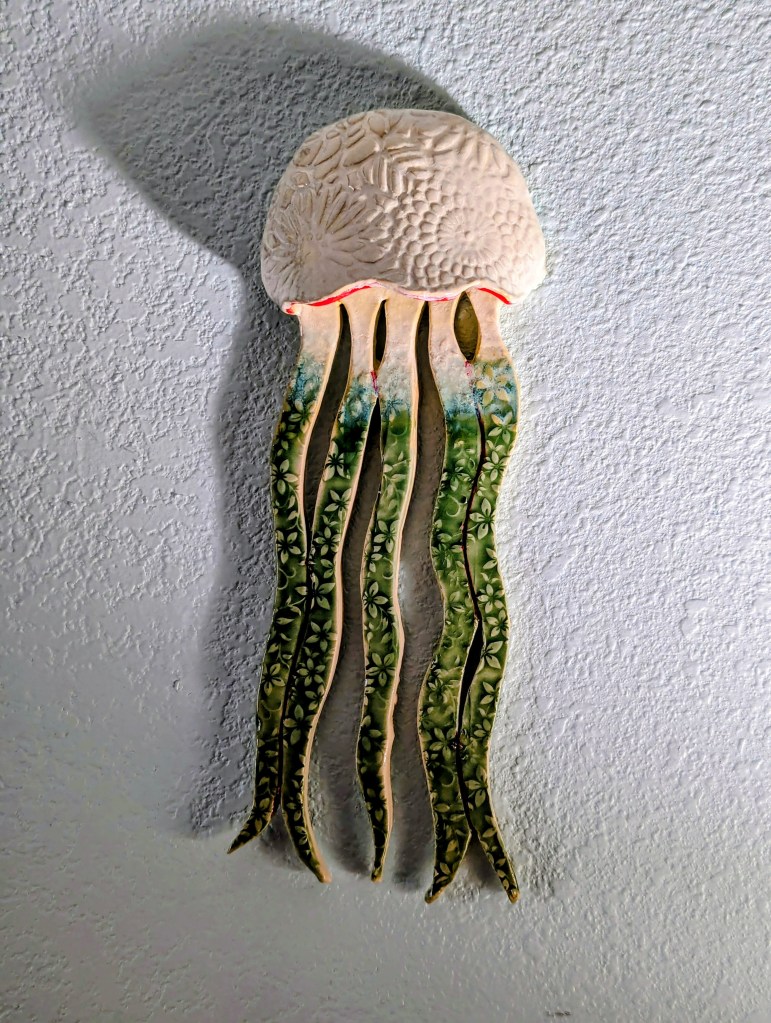 Ceramic wall-hanging jellyfish with green floral tentacles.