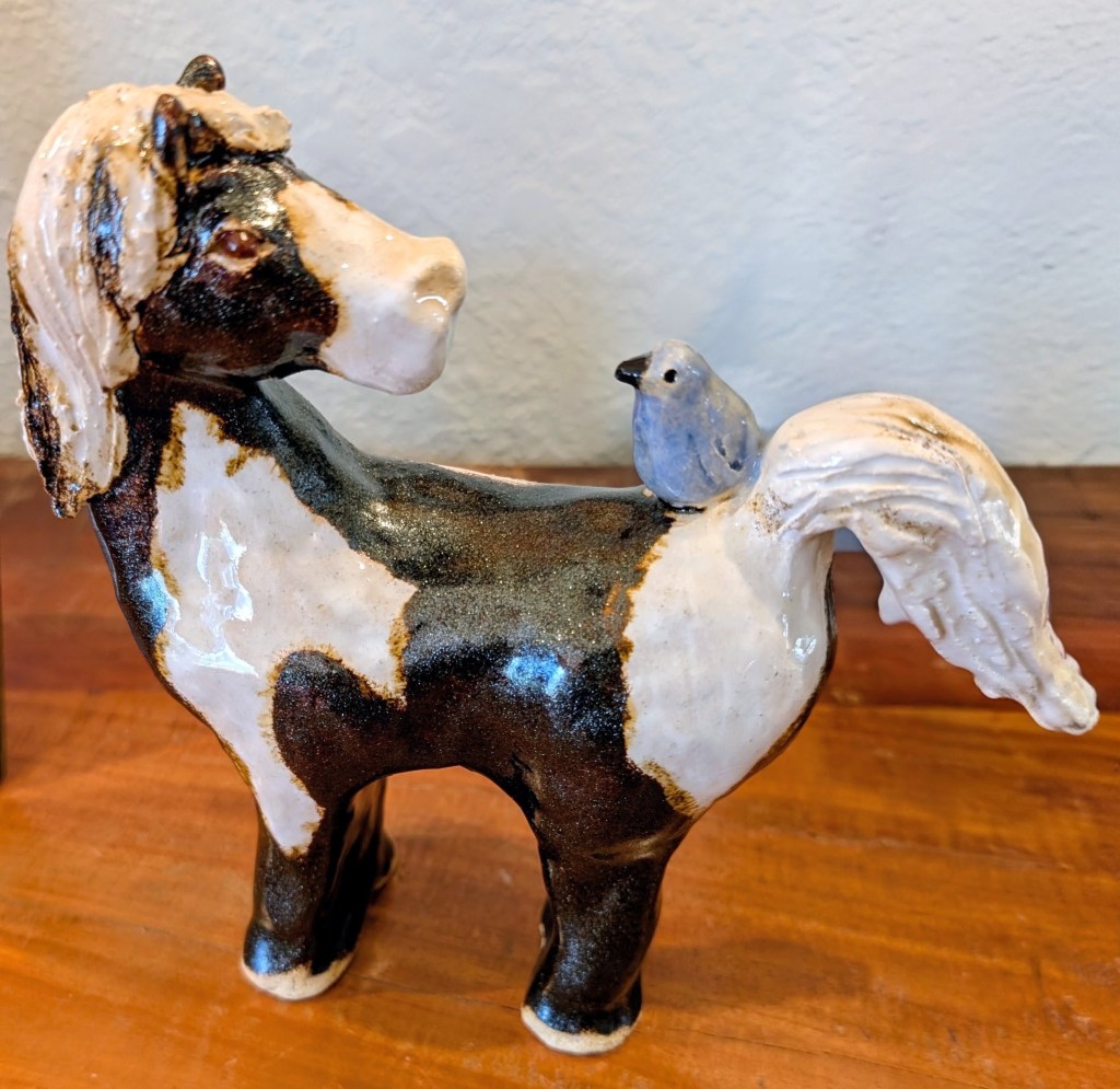 Ceramic horse artwork with a blue bird.
