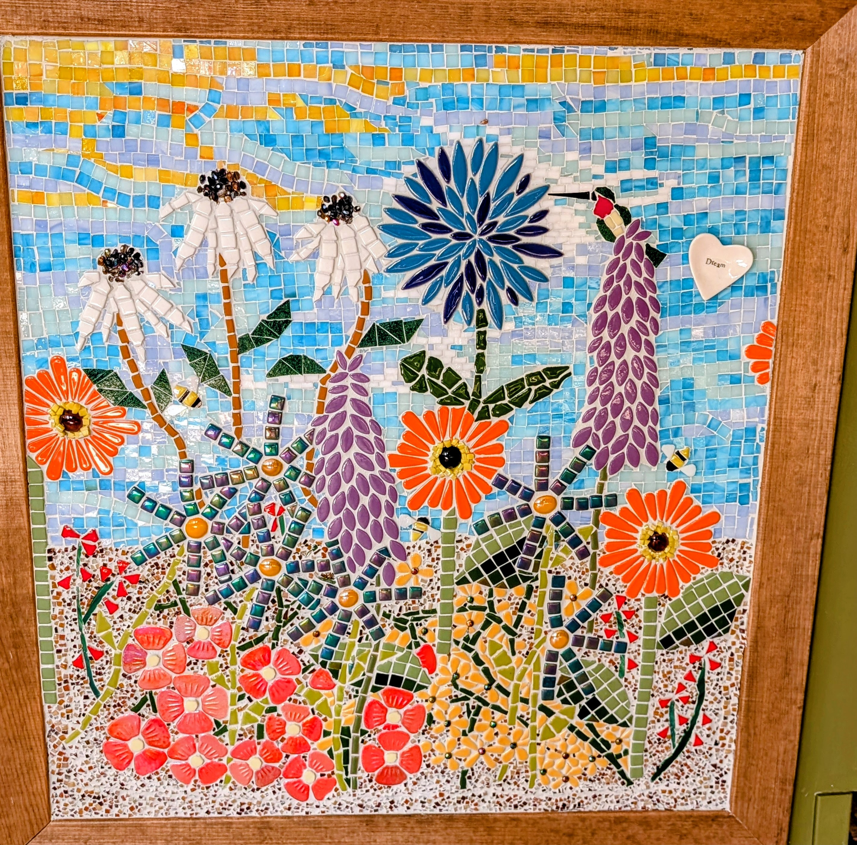 Colorful mosaic garden mural with flowers, dragonflies, bees, and a hummingbird.